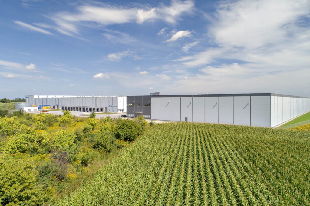 Exterior of Wroclaw IV Logistics Centre, showing fields and trees growing fruitfully.