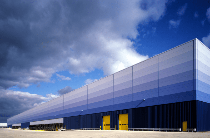 Blue gradient-panelled Amazon warehouse against a blue sky.