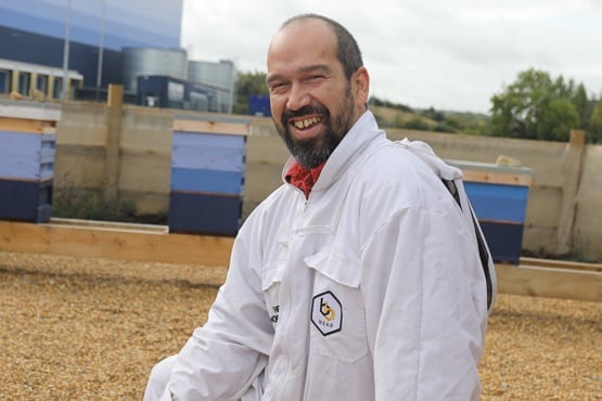 Man smiling in white bee keeping suit, working for the G-Hive,