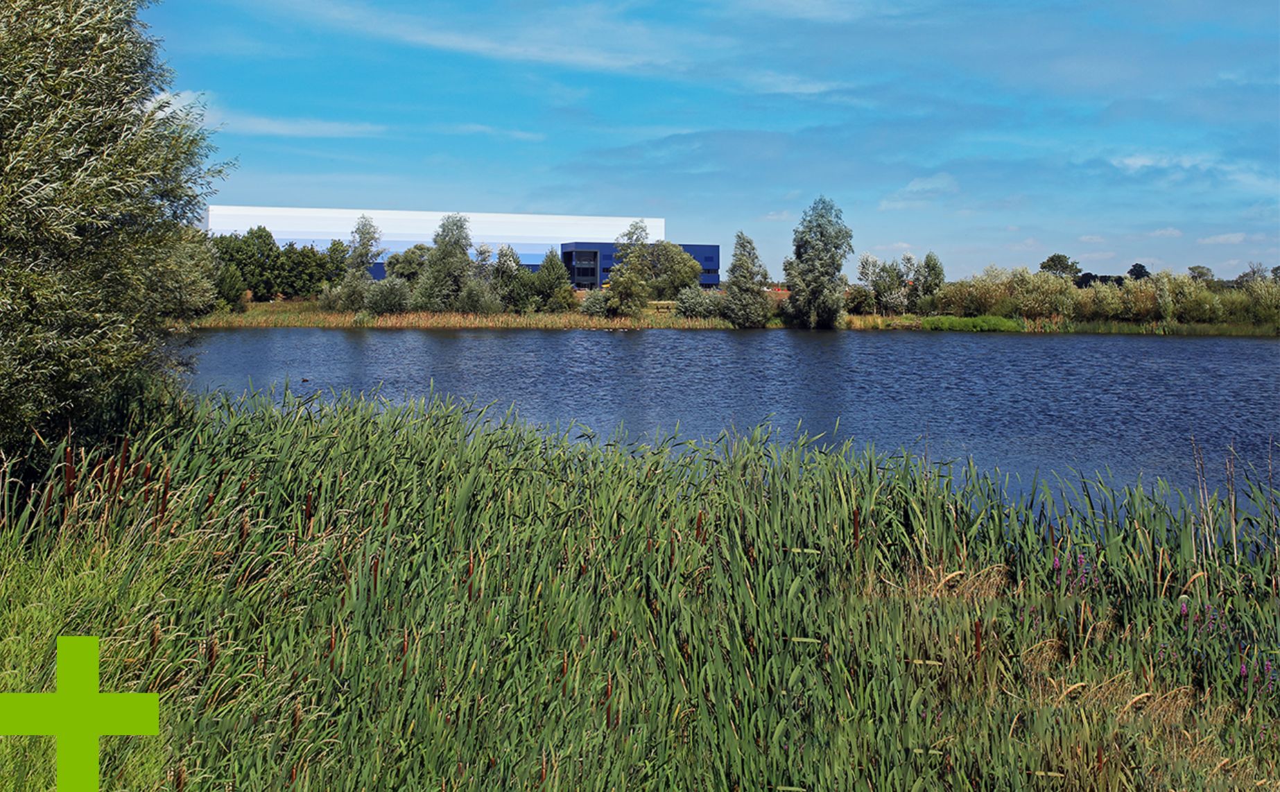 GLP logistics building seen across a river with grass and trees in the foreground.
