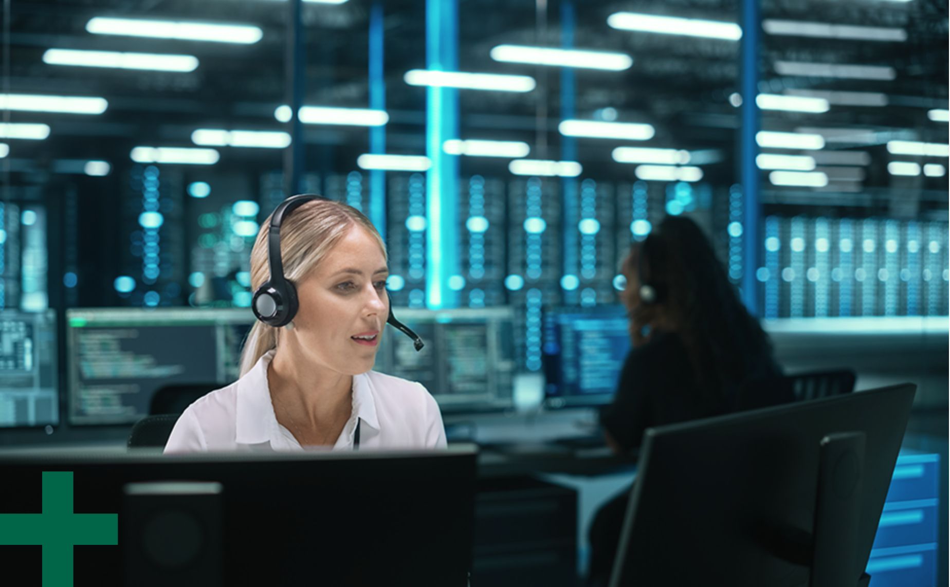 Woman sits at a computer desk and wears a headset while managing assets.