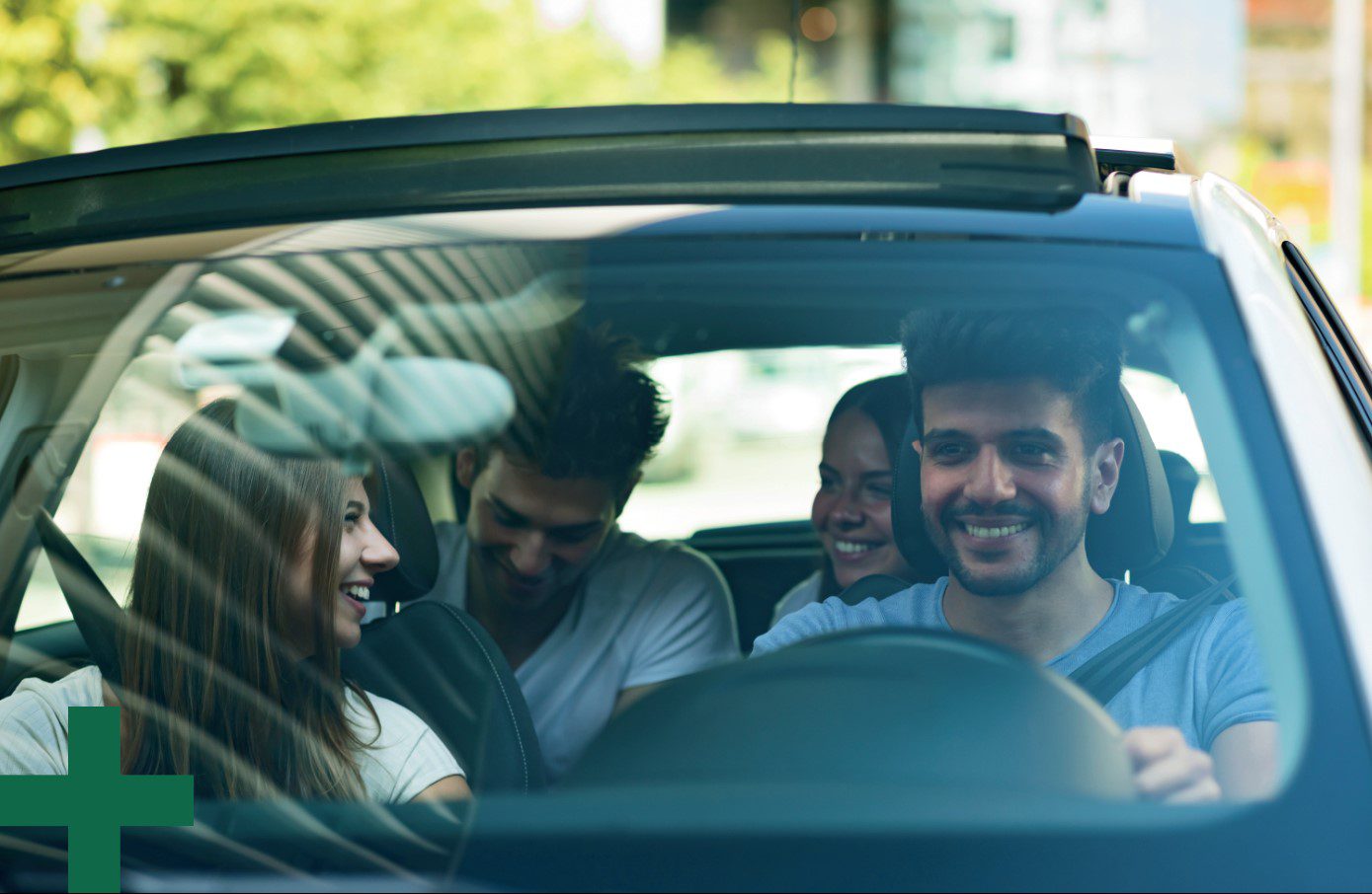 Four people in a car smile and laugh with each other.